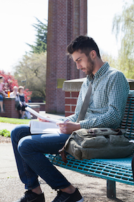 Student studying on a bench outside on campus.