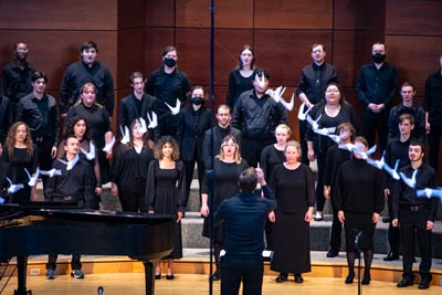 Clark College Choir dressed in formal attire singing on stage while directed by conductor