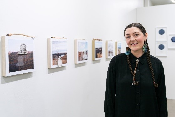 Epiphany Couch smiling, while showcasing her gallery of artwork in the background